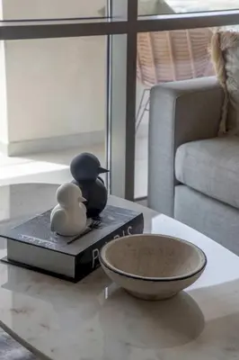 a table with a bowl and a bird on a book at Frank Porter - Vida Creek Beach in Dubai