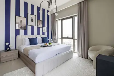 a bedroom with a large bed with blue and white stripes at Frank Porter - Vida Creek Beach in Dubai