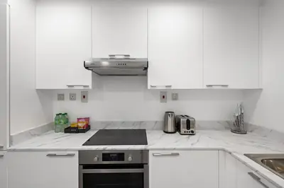a kitchen with white cabinets and a stove top oven at 1BR with Study City View in Bay Square B13 in Dubai