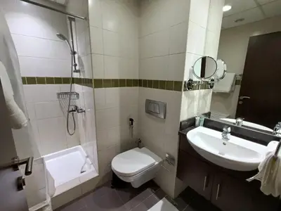 a bathroom with a toilet and a sink and a shower at Quill Residence - Canal View Spacious 3 bedroom Apartment in Dubai