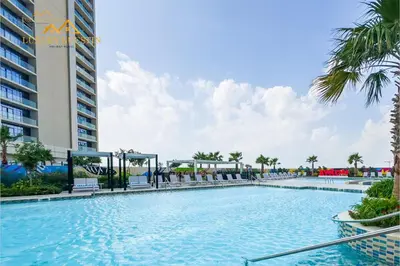 a swimming pool with palm trees and a building at Elegant 2-BR with Canal & City Views Pool Amenities in Dubai
