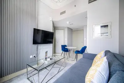 a living room with a blue couch and a tv at Elegant Escapes - Lavish 1B,Dubai Water Canal View in Dubai