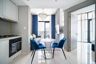 a kitchen with a table and two blue chairs at Elegant Escapes - Lavish 1B,Dubai Water Canal View in Dubai