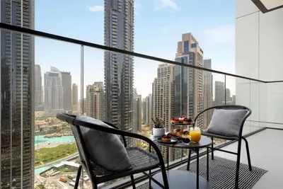 a balcony with a table and chairs and a view of a city at Luxury High Floor Apartment with Downtown Boulevard View Opposite Dubai Mall in Dubai