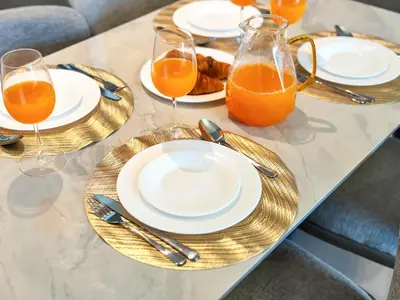 a table with plates and glasses of orange juice at BRAND-NEW 1BR in DOWNTOWN I Direct DUBAI MALL Access I Balcony & Stunning Pool in Dubai