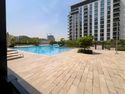 a swimming pool in front of a tall building at Executive Residence-Dubai Hills by Serenity Living in Dubai