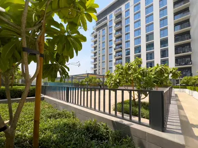 a fence with trees in front of a building at Executive Residence-Dubai Hills by Serenity Living in Dubai