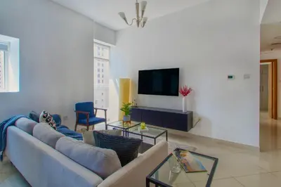 a living room with a blue couch and a tv at ShoresInn - Elegant 2BR with Dubai Marina View in Dubai