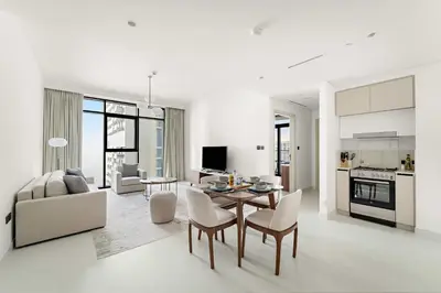 a white living room with a table and chairs at Silkhaus 1BDR in Marina Vista with Private Beach in Dubai