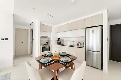 a kitchen with a table and chairs and a refrigerator at Silkhaus 1BDR Marina Vista with Private Beach Access in Dubai