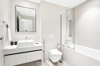 a white bathroom with a sink and a mirror at Silkhaus 1BDR Sea View Retreat with Private Beach in Dubai