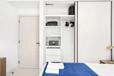 a bedroom with a bed and a white closet at Silkhaus 1BDR Sea View Retreat with Private Beach in Dubai