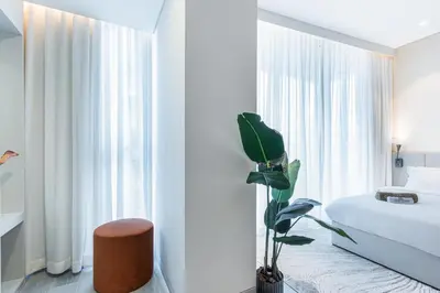a bedroom with a bed and a plant in front of a window at Luxe Central Marina Studio with Rooftop Pool in Dubai