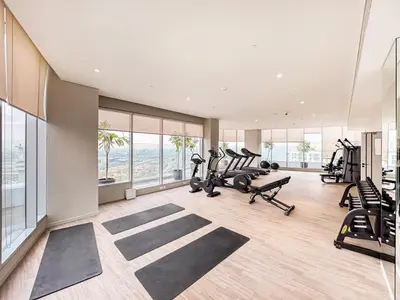 a gym with treadmills and ellipticals in a room with windows at Luxe Central Marina Studio with Rooftop Pool in Dubai