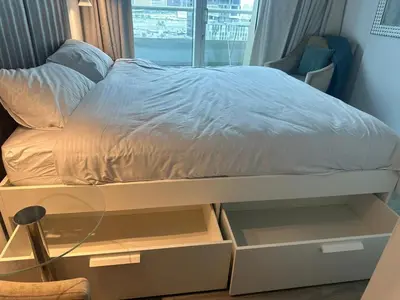 a bed with two drawers and a bed with white sheets at Damac canal views building in Dubai