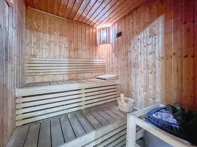 a wooden sauna with a bench and a bucket at ShoresInn - Luxury 1BR with Marina View in Dubai