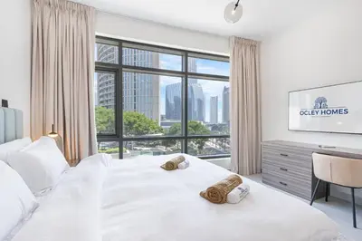 a bedroom with a white bed with a large window at Elegant & Cozy 2BR Home in the Heart of Downtown in Dubai