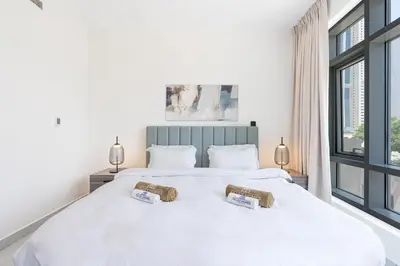 a bedroom with a large white bed with windows at Elegant & Cozy 2BR Home in the Heart of Downtown in Dubai