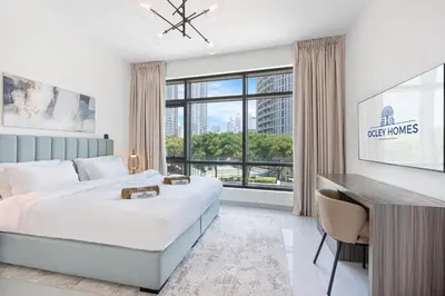a bedroom with a bed and a desk and a window at Elegant & Cozy 2BR Home in the Heart of Downtown in Dubai