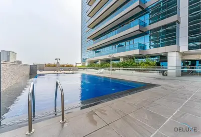 a swimming pool in front of a building at Stylish 1BR Apartment at Orchid Residence, Al Barsha South by Deluxe Holiday Homes in Dubai
