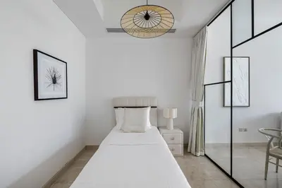 a white bedroom with a bed and a chair at 1BR with Study City View Bay Square in Dubai