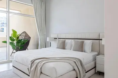 a white bedroom with a large bed and a window at 1BR with Study City View Bay Square in Dubai