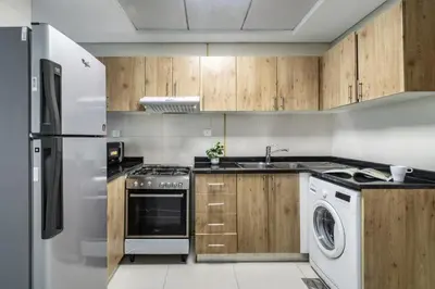 a kitchen with white appliances and wooden cabinets at ShoresInn - Chic Waterfront Living in Dubai Marina in Dubai