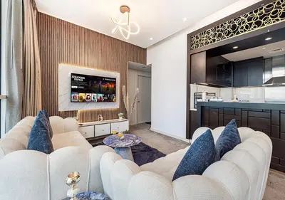 a living room with a white couch and a kitchen at Burj Khalifa View! 2 Bedroom Luxe Apartment with 4 minute walk to Dubai Mall! Pool and Sauna Access! in Dubai