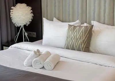 a white bed with towels and pillows on it at Burj Khalifa View! 2 Bedroom Luxe Apartment with 4 minute walk to Dubai Mall! Pool and Sauna Access! in Dubai