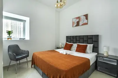 a bedroom with a bed and a chair and a window at ShoresInn - Serene Retreat with Waterfront Views in Dubai