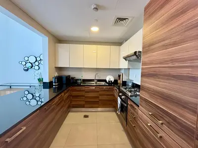 a kitchen with wooden cabinets and a counter top at Sparkle Tower Panoramic Marina View 1BR in Dubai