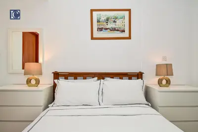 a white bedroom with two nightstands and a bed at Luxury Escapes - Spacious 1BR with Pool view - Ghozlan 2 The Greens in Dubai