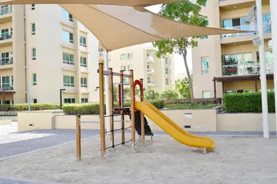 a playground with a slide in front of a building at Luxury Escapes - Spacious 1BR with Pool view - Ghozlan 2 The Greens in Dubai