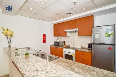a kitchen with a sink and a refrigerator at Luxury Escapes - Spacious 1BR with Pool view - Ghozlan 2 The Greens in Dubai
