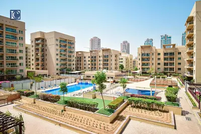 an apartment complex with a swimming pool and buildings at Luxury Escapes - Spacious 1BR with Pool view - Ghozlan 2 The Greens in Dubai
