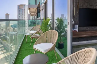 a balcony with chairs and a flat screen tv at 5 Star Apartment with Burj View Infinity Pool and Gym Spa in Dubai