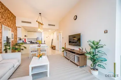 a living room with a white couch and a kitchen at Premium 1BR at DAMAC Hills Loreto 1B in Dubailand by Deluxe Holiday Homes in Dubai