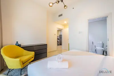 a bedroom with a bed and a yellow chair at Premium 1BR at DAMAC Hills Loreto 1B in Dubailand by Deluxe Holiday Homes in Dubai