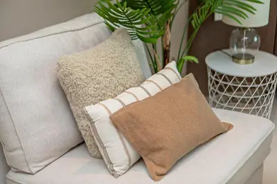 a white couch with two pillows on it with a plant at Modern and Cozy Studio at Seven Palm Prime Location in Dubai
