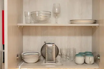 a shelf with bowls and plates and glasses on it at Modern and Cozy Studio at Seven Palm Prime Location in Dubai