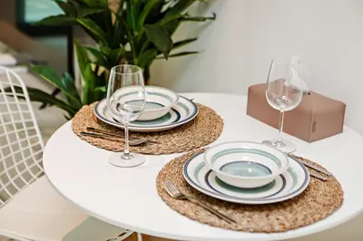 a white table with plates and wine glasses on it at Modern and Cozy Studio at Seven Palm Prime Location in Dubai