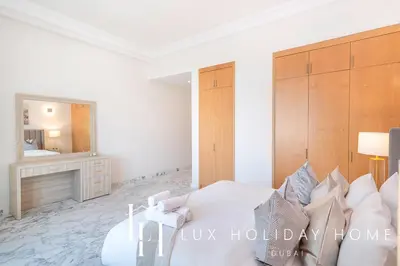 a white bedroom with a bed and a mirror at LUX The Shoreline Palm Island Penthouse in Dubai