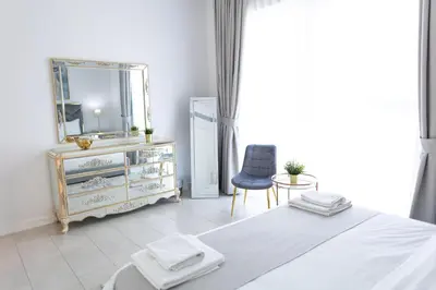 a bedroom with a bed and a mirror and a chair at La Vie Beach front JBR apartment by Happy Season in Dubai