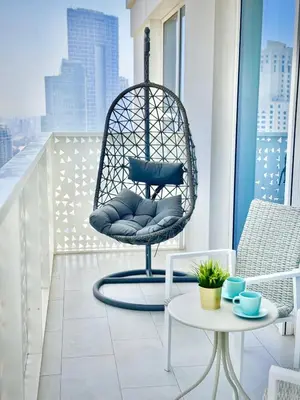a hanging chair on a balcony with a view of a city at La Vie Beach front JBR apartment by Happy Season in Dubai