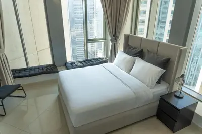 a bedroom with a large white bed with large windows at Downtown Gem, Full Burj Khalifa & Dubai Fountain Views, Luxury Amenities in Dubai