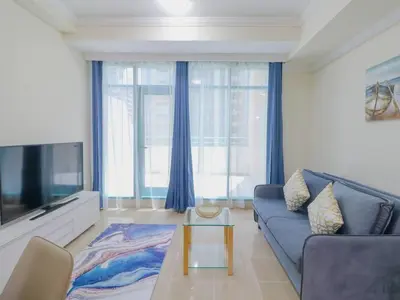 a living room with a blue couch and a tv at Vibrant 1 Bedroom at Barasti-Dubai Marina in Dubai