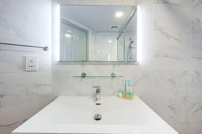 a white bathroom with a sink and a mirror at Comfortable Studio With Dubailand Vibes in Dubai