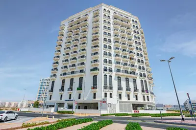 a tall white building with balconies on the side of it at Comfortable Studio With Dubailand Vibes in Dubai