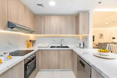 a kitchen with wooden cabinets and a sink at Vacay Lettings - Spacious 3 Bedroom at JBR walk in Dubai