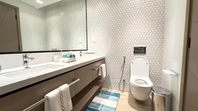 a bathroom with a sink and a toilet and a mirror at Luxury 2BR w Waterfront View & Smart Controls by Vibel in Dubai